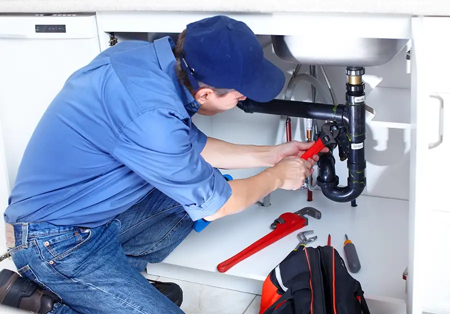 Plumber repairing pipes under kitchen sink - Springfield, IL